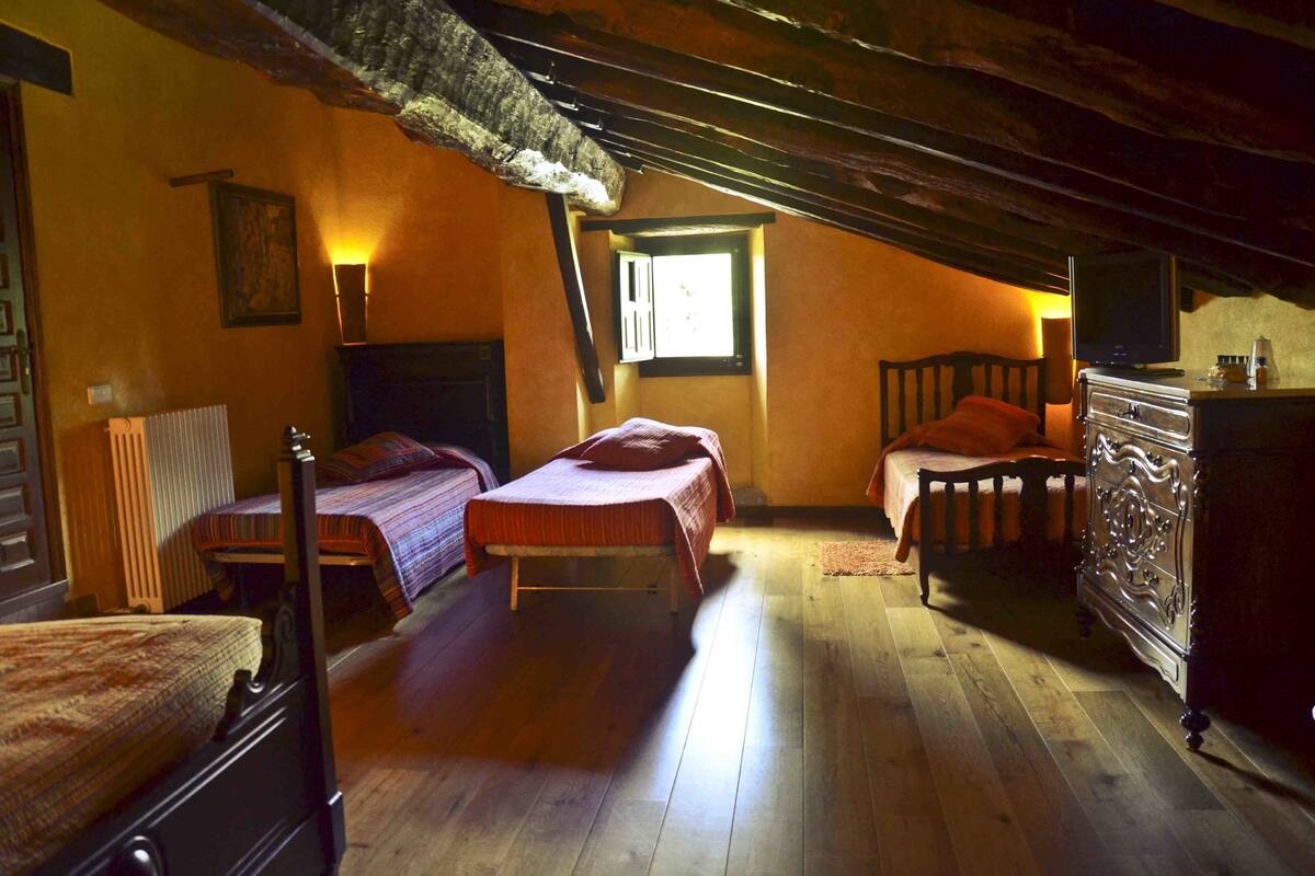 Un dormitorio acogedor en el ático con dos camas, un aparador y un televisor.