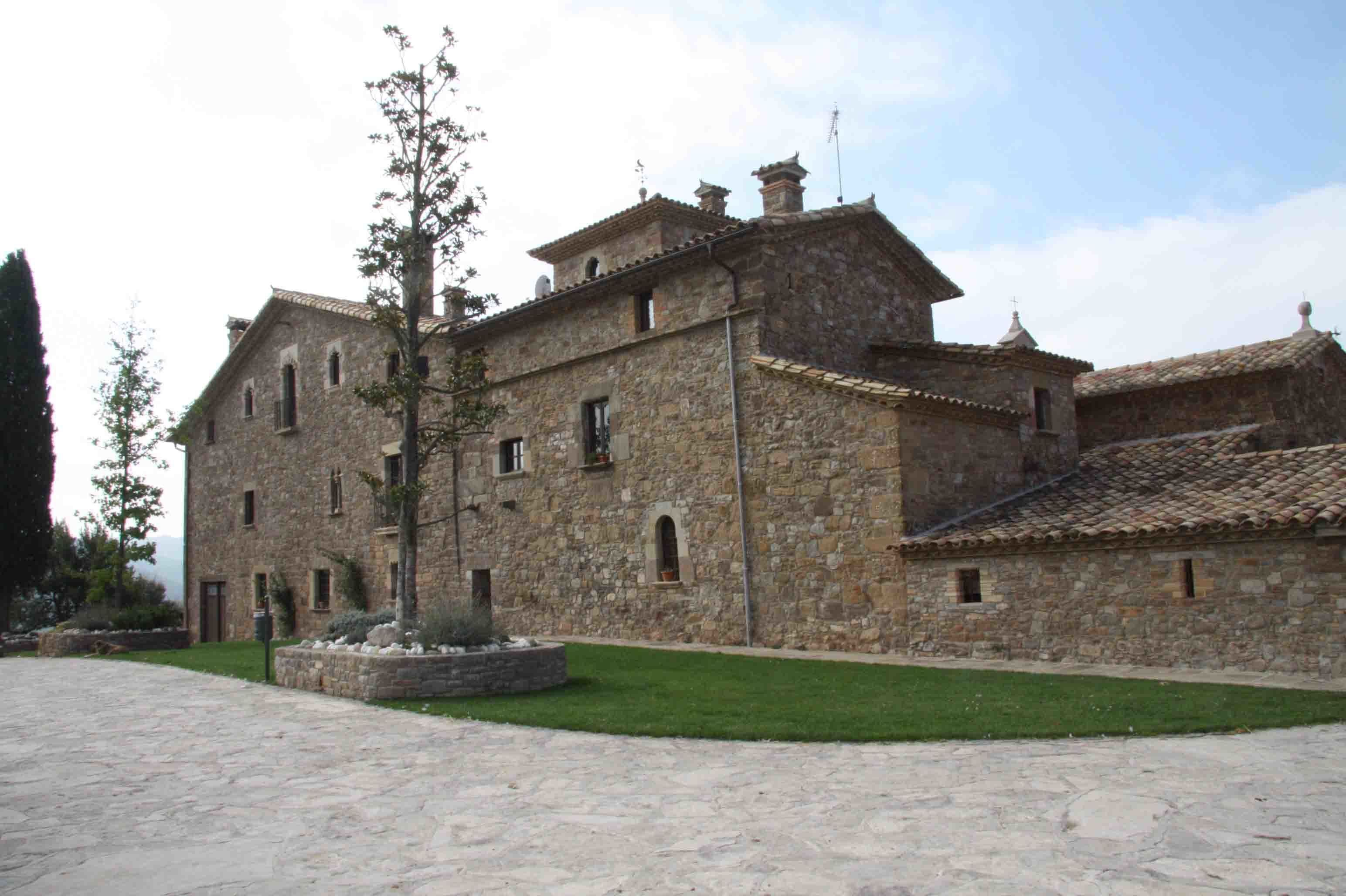 Un edificio de piedra con patio interior, que presenta un árbol central y un camino de piedra.