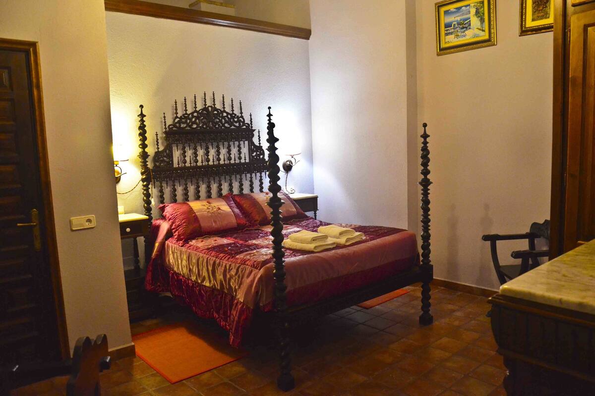 Un dormitorio con cama con dosel, una mesita de noche, una silla y una pequeña mesa.