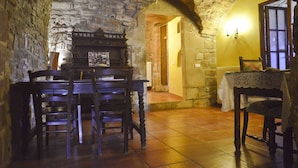 Un comedor rústico con paredes de piedra, una mesa de madera y sillas.