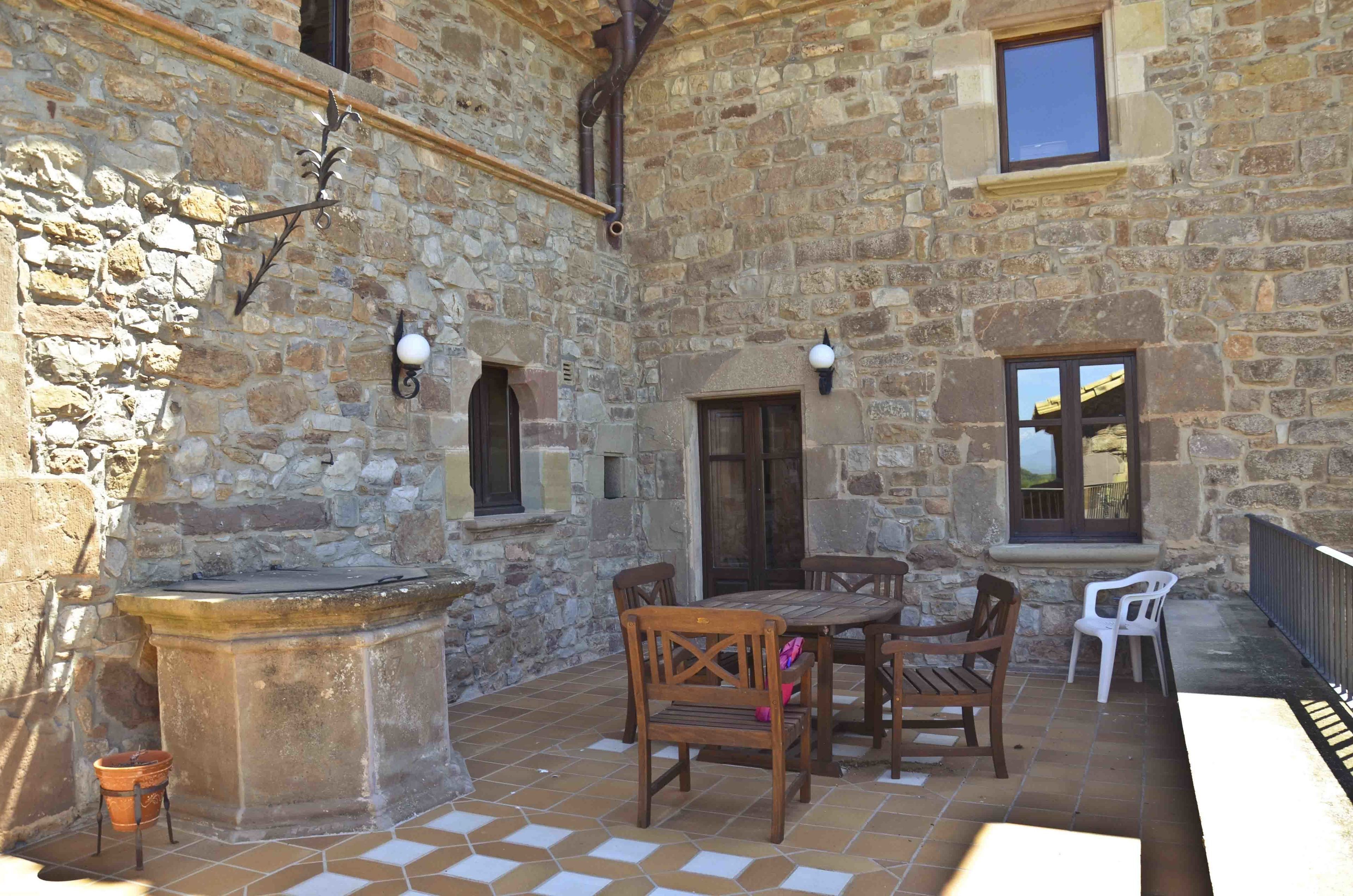 A stone building with a courtyard, outdoor seating, and a stone fireplace.