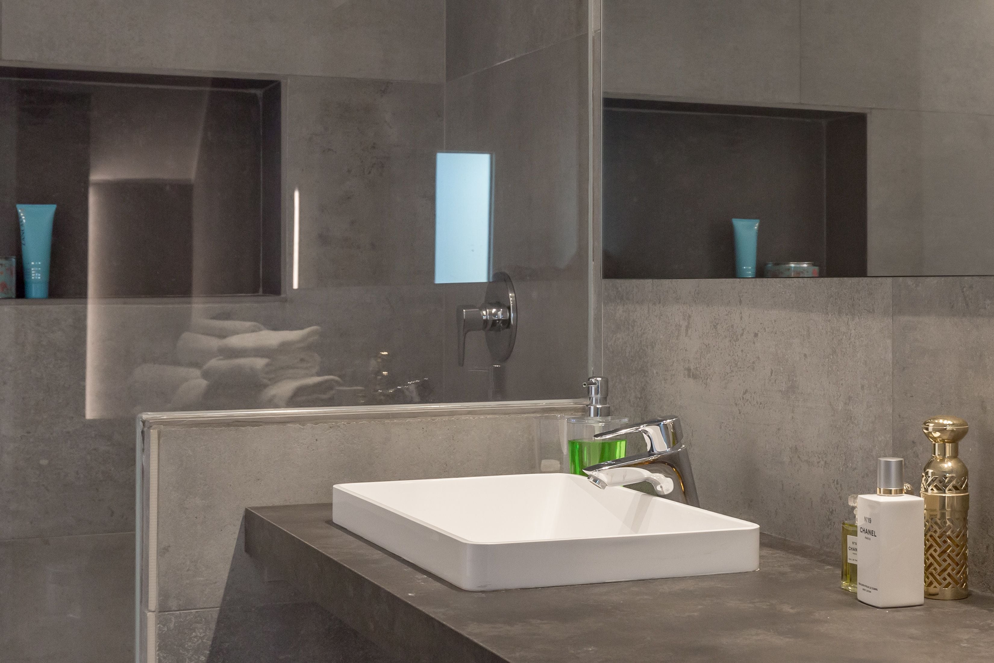 A modern bathroom with a large mirror, a white sink, and a shower area.