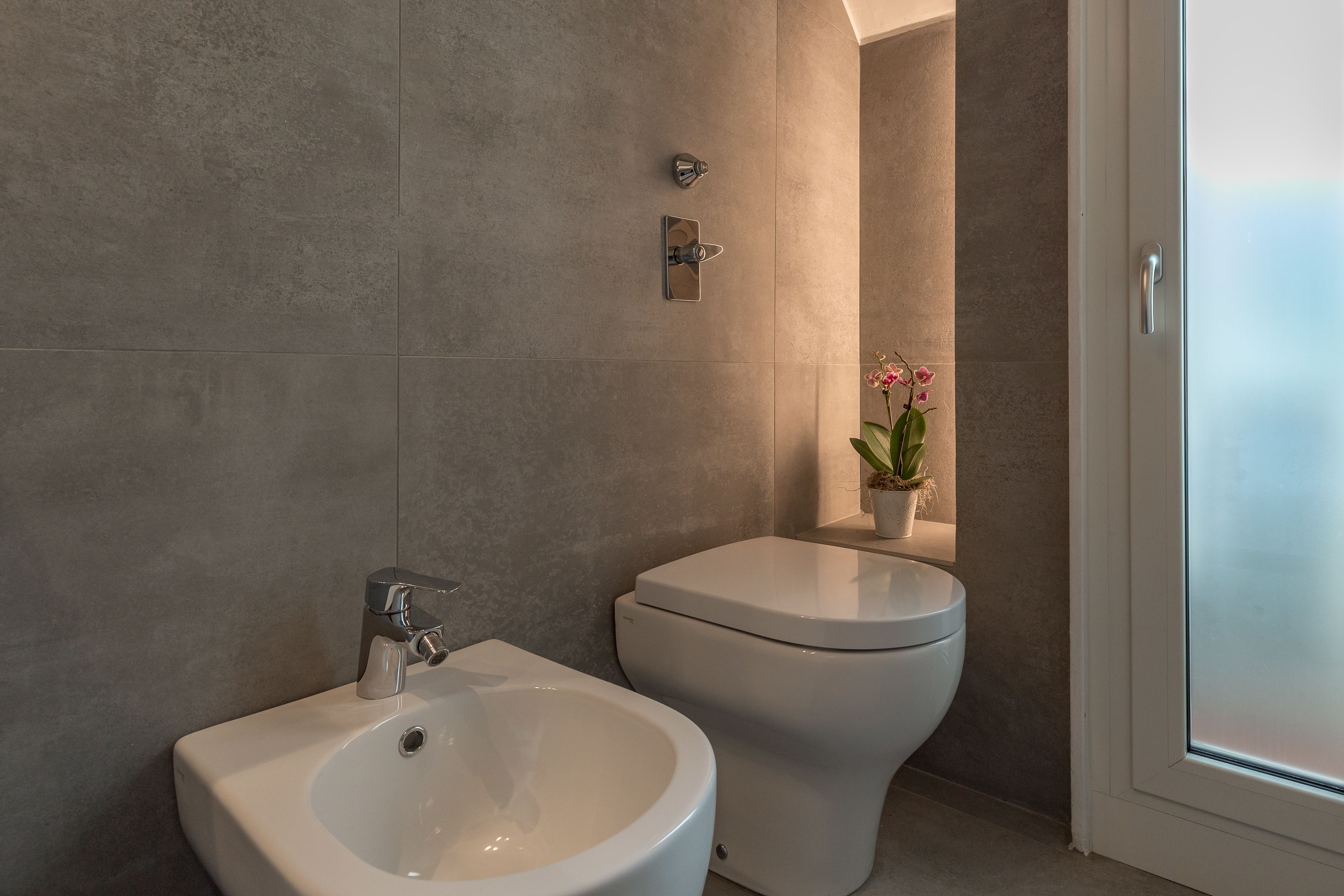 Une salle de bain moderne avec un bidet, des toilettes et une plante en pot.