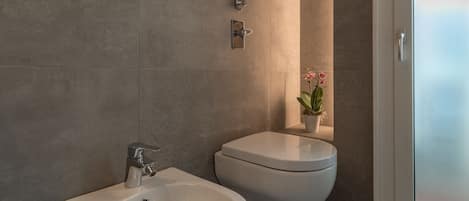 Une salle de bain moderne avec un bidet, des toilettes et une plante en pot.