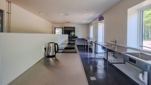 A modern kitchen with a long countertop, built-in appliances, and a window providing natural light. - Tønder Byferie (Tonder)