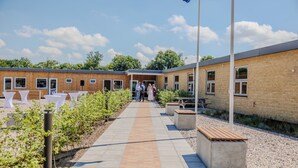 A building with a brick exterior, a paved walkway, and outdoor seating areas. - Tønder Byferie (Tonder)