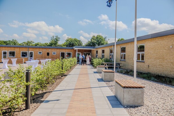 A building with a brick exterior, a paved walkway, and outdoor seating areas.