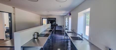 A modern kitchen with stainless steel appliances, a long counter, and a window providing natural light.