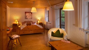 A cozy room with a wooden bed, a chair, a table, and a window.