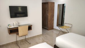 Una habitación de hotel con una cama, un escritorio con silla, televisor, armario y espejo.
