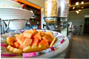 Un buffet con una varietà di frutta, tra cui melone e ananas.
