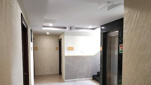 Un pasillo con piso de color claro, pared de mármol y una puerta con el número 405.