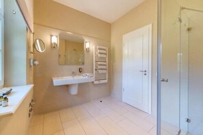 Une salle de bain équipée d’un lavabo, d’un miroir, d’un porte-serviettes et d’une cabine de douche en verre.