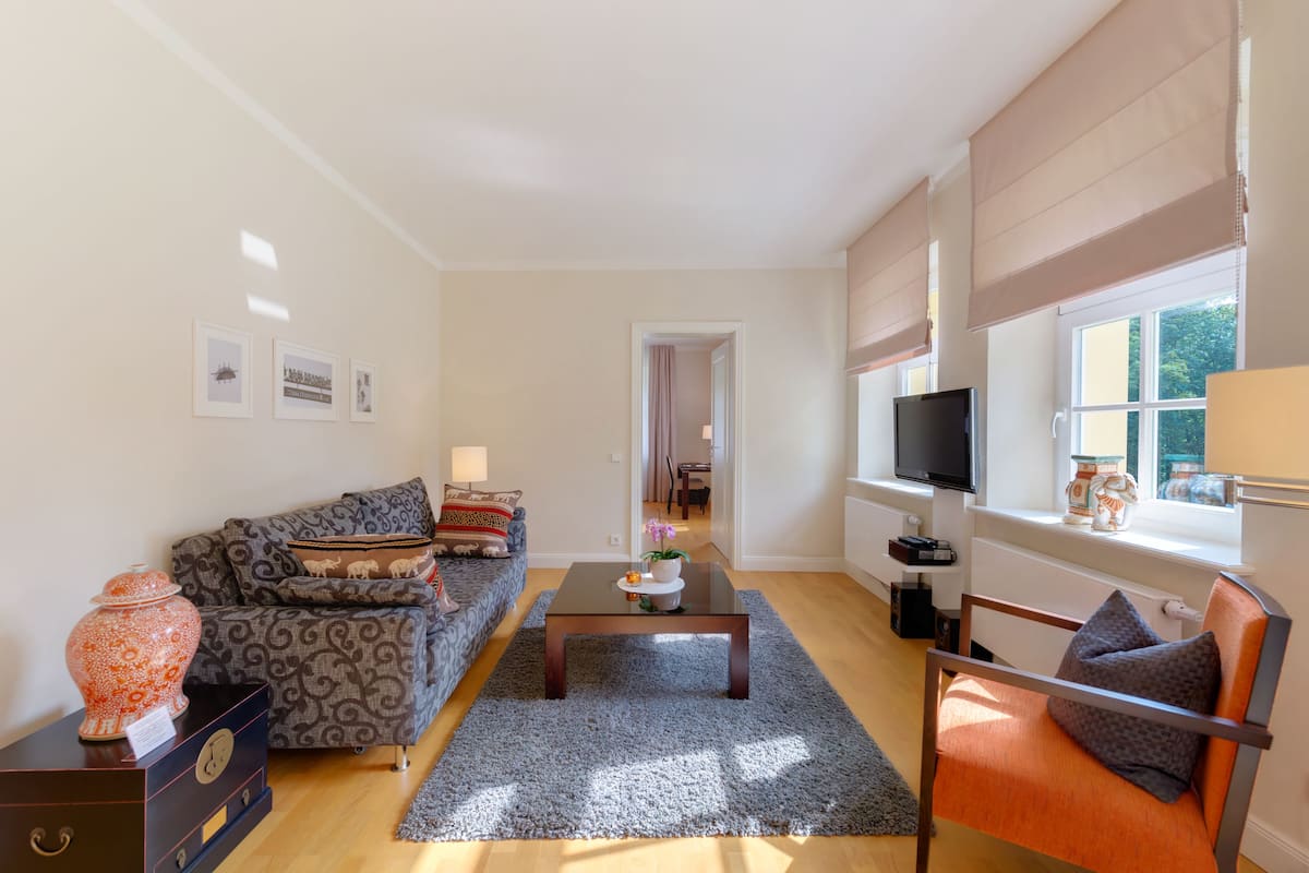 Sala de estar com sofá, poltrona, mesa de centro e televisão.