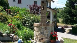 A white house with a stone chimney, surrounded by a garden with red flowers and a stone wall. - Agriturismo Persichitti (Torricella Peligna)