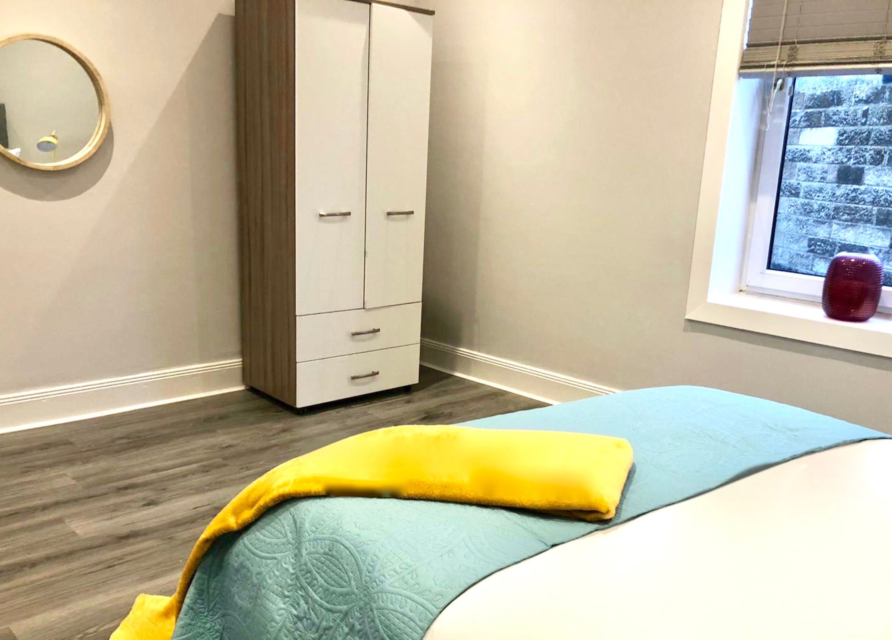 Een slaapkamer met een bed, een kledingkast, een raam met uitzicht en een spiegel.