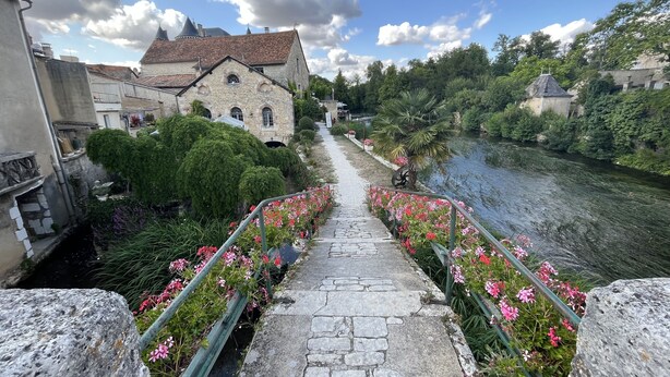 A stone pathway leading to a historic building with a river on one side. - Les Bruyères (Verteuil-sur-Charente)