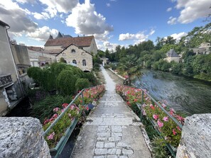A stone pathway leading to a historic building with a river on one side. - Les Bruyères (Verteuil-sur-Charente)