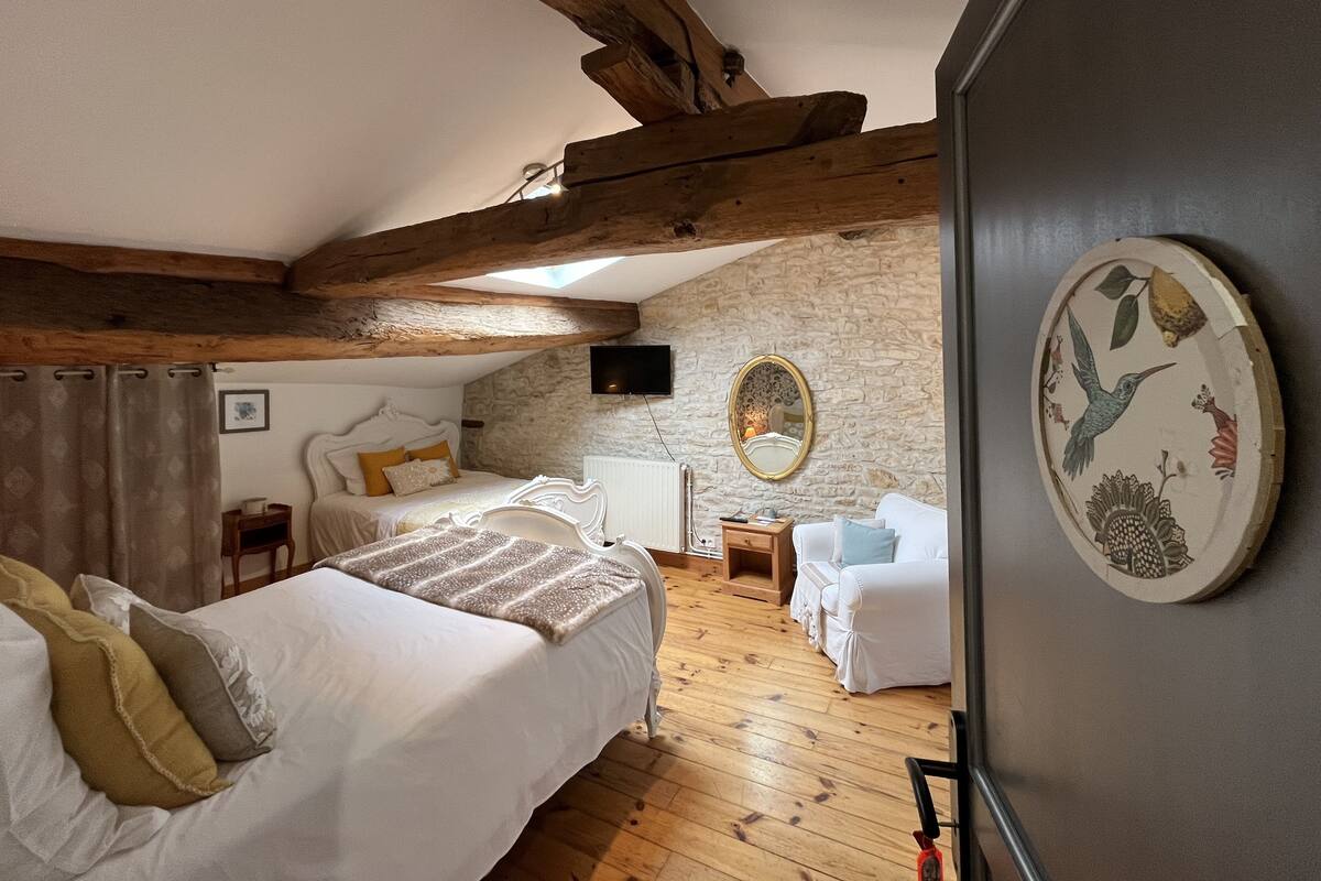 Een slaapkamer met een bed, een dressoir, een spiegel en een stenen muur.