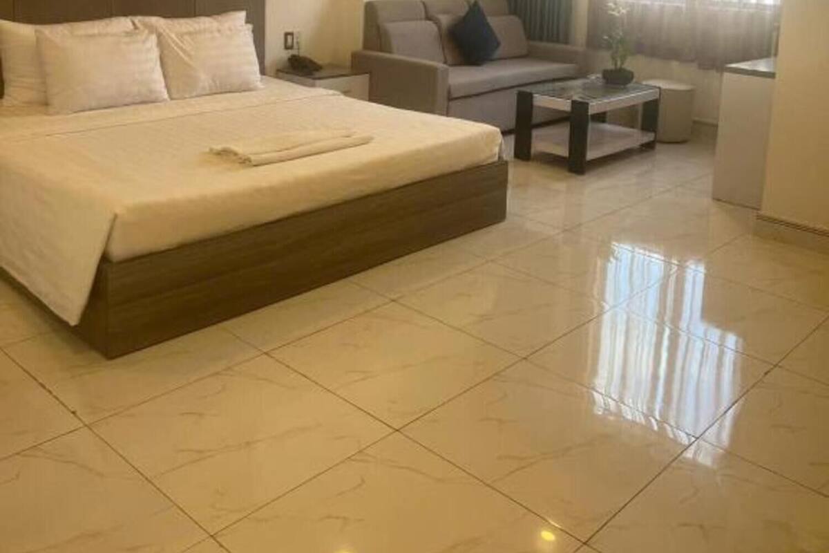 Une chambre d’hôtel avec un grand lit, un canapé, une table basse et une fenêtre avec des rideaux.
