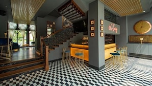 A bar area with a checkered floor, a staircase, and a neon sign. - Raajkutir - IHCL SeleQtions (Kolkata)