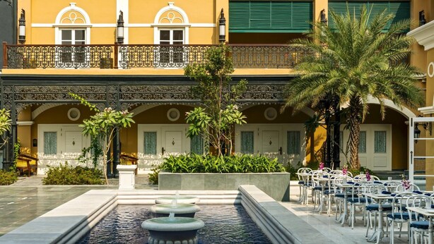 A courtyard with a fountain, outdoor seating, and a building with balconies and windows. - Raajkutir - IHCL SeleQtions (Kolkata)