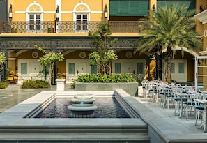 A courtyard with a fountain, outdoor seating, and a building with balconies and windows.
