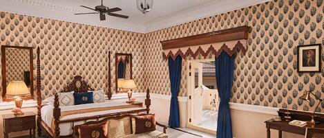 A spacious bedroom with a large bed, a sitting area, and a desk.