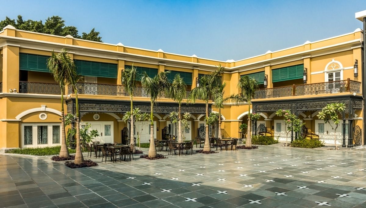 A courtyard with a tiled floor, palm trees, and outdoor seating areas.
