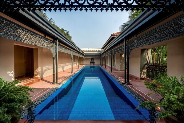 A pool area with a central water feature, surrounded by ornate metal railings and potted plants. - Raajkutir - IHCL SeleQtions (Kolkata)