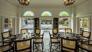A dining area with a view of the street, featuring a large table with chairs and chandeliers. - Raajkutir - IHCL SeleQtions (Kolkata)
