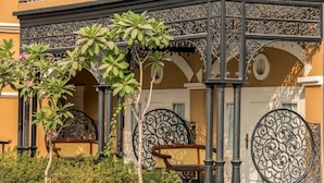An outdoor area with a wrought iron gate, a bench, and a small tree. - Raajkutir - IHCL SeleQtions (Kolkata)