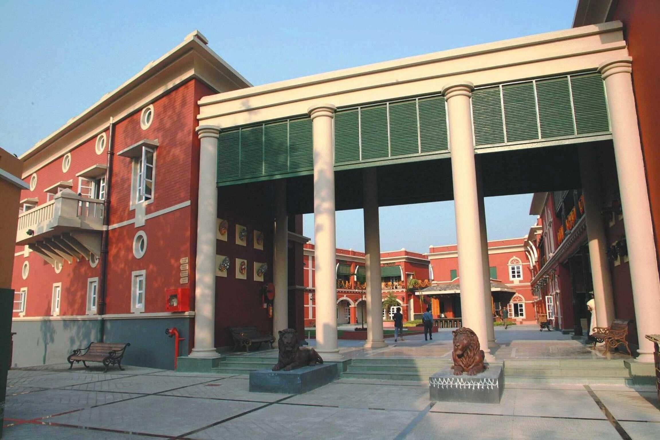 A red building with columns and a statue in the center.