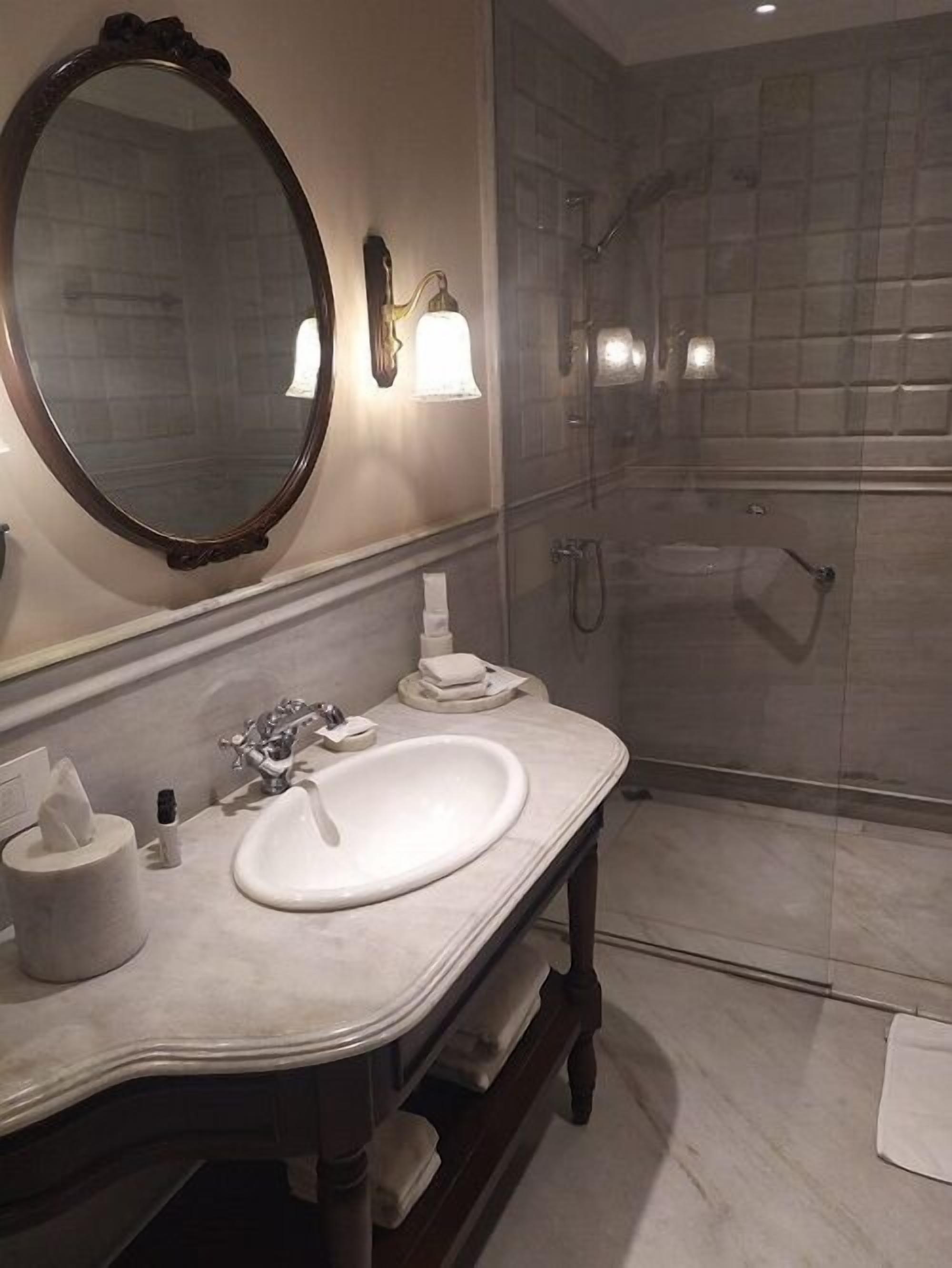Un baño con un espejo grande, un lavabo, tocador y zona de ducha.
