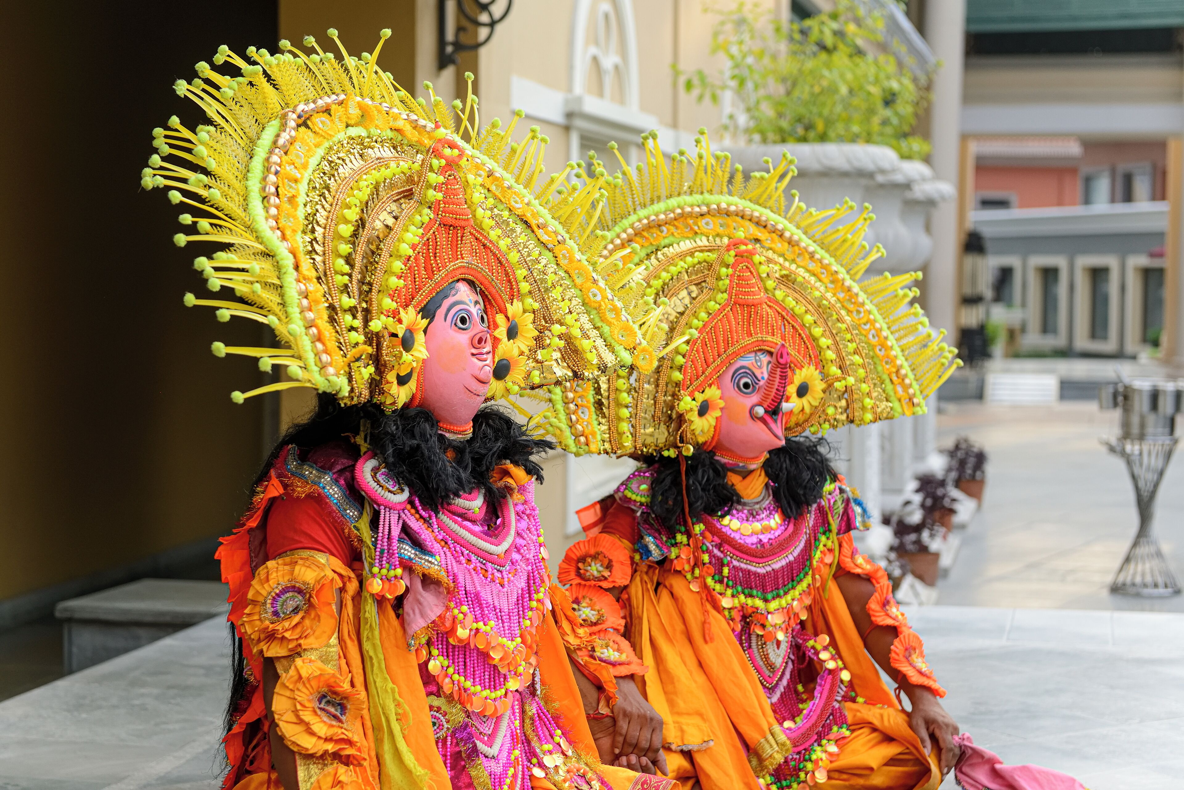 Dos personas con trajes elaborados y tocados adornados con detalles de cuentas.