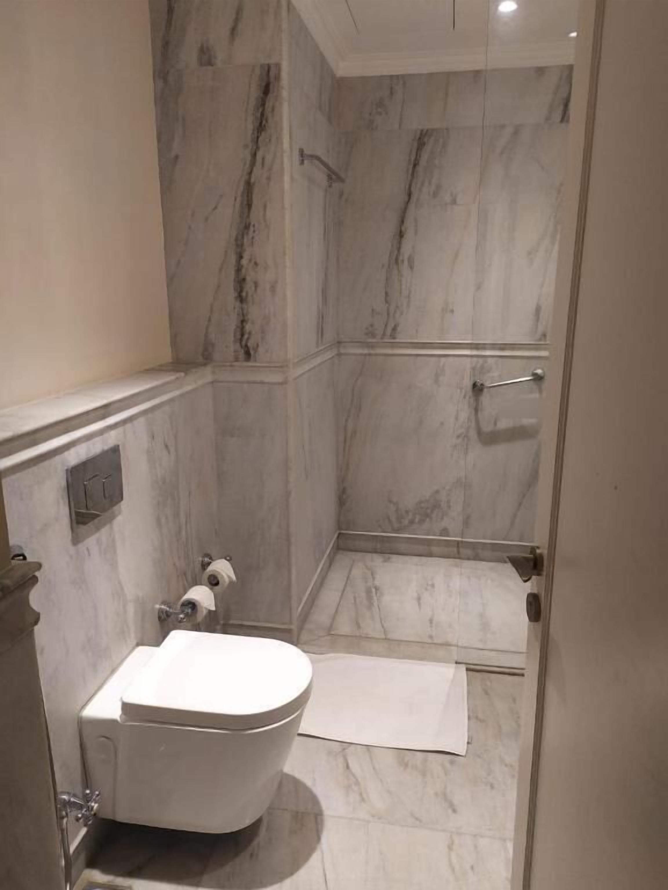 A bathroom with a toilet, a shower, and marble walls.