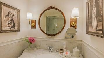 A bathroom with a marble sink, two wall-mounted mirrors, and framed pictures on the walls.