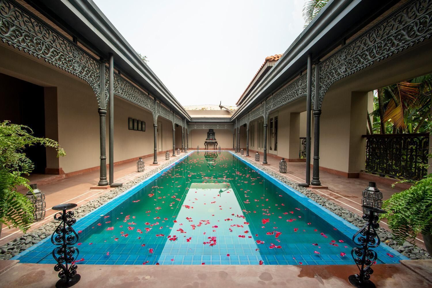 A pool with a central walkway, surrounded by ornate columns and a tiled floor.