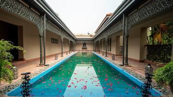 A pool with a central walkway, surrounded by ornate columns and a tiled floor.