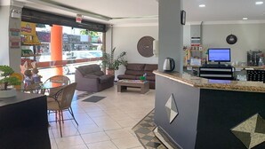 A hotel lobby with a reception desk, seating area, and a view of the street. - Arco do Sol Parque Hotel (Camboriú)