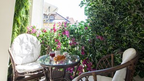 A cozy outdoor seating area with wicker chairs and a glass table, surrounded by lush greenery and purple flowers. - Filip Palace Luxurious Apartment (Ljubljana)