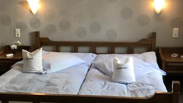 A double bed with two pillows, a wooden headboard, and two wall-mounted light fixtures.