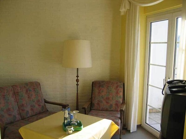 Une chambre d’hôtel avec un lit, une petite table avec une lampe, une télévision et une fenêtre avec des rideaux.