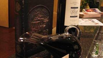 Un'area reception di un hotel con una bottiglia di vino, una scultura di vetro decorativa, una candela accesa e un quadro incorniciato sul bancone.