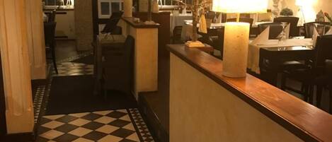 A hotel lobby with a checkered floor, a reception desk, and a staircase leading to the upper floor.