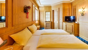A hotel room with a large bed, wooden paneling, a television, and a window. - Hotel Jauch's Löwen (March)