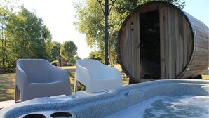 Ein Whirlpool mit zwei weißen Stühlen, einem Holzfass und einer Steinkonstruktion.