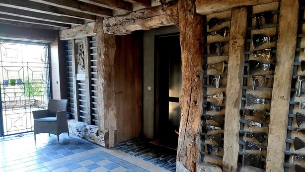 Ein rustikales Interieur mit Schachbrettboden, Holzbalken und einem Metallgitter.