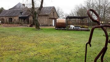 Ein rustikales Haus mit einem großen Holzfass und einer überdachten Sitzterrasse.