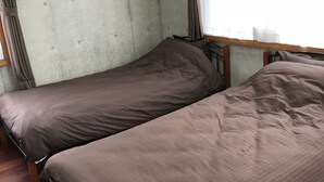 A room with two single beds, a window with curtains, and an air conditioning unit mounted on the wall. - Biimata house (Nago)